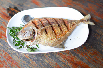 Fried cotton fish with fish sauce placed on a white plate ready to eat.