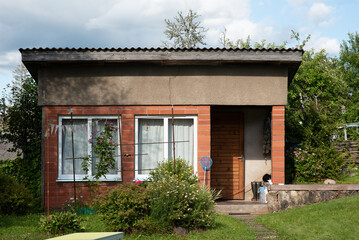 landscape with wooden shed, garden house, various summer flowers