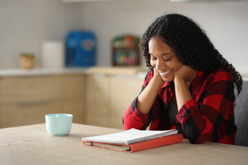 Happy black student learning reading notes in the kitchen