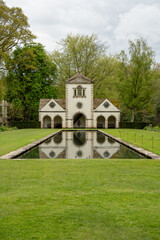 an old white pin mill reflected in a still water pond