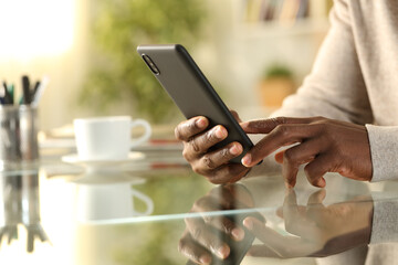 Black man hands checking cell phone at home on a desk