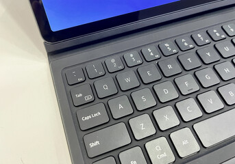 Tablet attached to gray colored keyboard. Modern gadget isolated on horizontal white desk surface background.