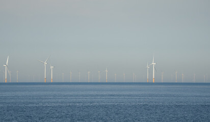 many tall wind turbines of an offshore wind farm, in action, Gwynt y M&ocirc;r (Sea wind) 576-megawatt offshore wind farm with 160 x 150m high turbines in Colwyn Bay Wales