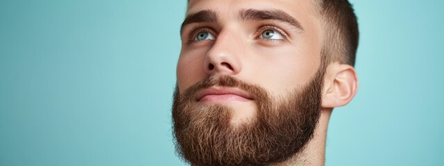Fototapeta premium A tight shot of a bearded man with intense blue eyes gazing upward