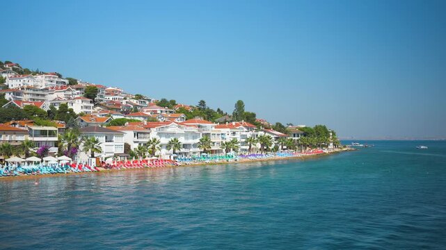 Kinaliada Island in Adalar district of Istanbul with the public beach and many houses on the hill. View from the ferry in the Sea of Marmara