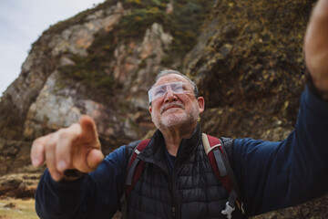 Active senior man wearing smart glasses and dancing at beach