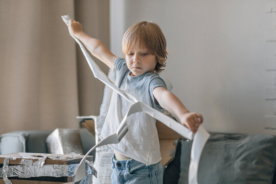 Boy with foil paper making astronaut suit in living room