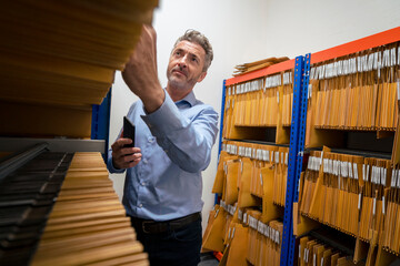 Mature businessman removing files from archives storage room