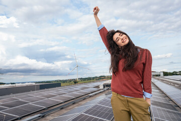 Happy businesswoman with hand raised standing on terrace with solar panels
