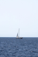 Fototapeta premium Sailboat on the horizon. Blue sea. Minimalist photo idea concept. Luxury yacht.