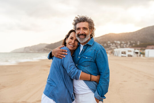 Smiling heterosexual couple hugging at beach - Powered by Adobe