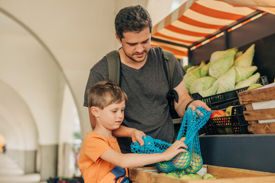 Father and son buying apples from market stall