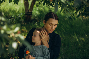 Obraz premium Mother and daughter family in a summer green garden together, happy and hugging