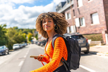 Latin woman walking along street using mobile phone