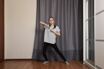 Teenage girl dancing at home, teenager enjoying an active lifestyle, smiling student dancing to online music.