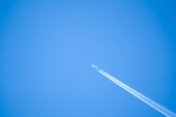 high altitude twin engine contrails (jet airplane vapour trails) across a deep blue clear sky