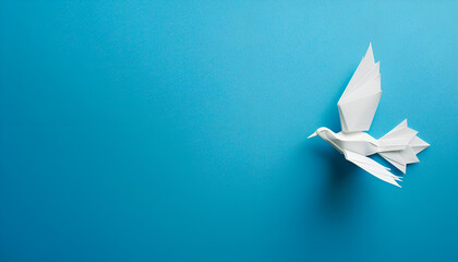 Obraz premium White origami pigeon on a blue paper background, peace or freedom concept, paper art work
