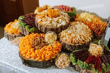 A table is covered with a variety of snacks and appetizers, including chips, pretzels, and vegetables. The table is set up for a party or gathering