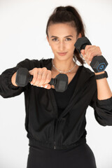 Young girl posing with dumbbells for power training, indoors. athlete wearing black leggings and shirt