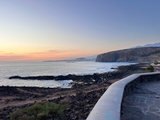 Dramatic sky and frothy ocean hitting the volcanic rocks, before the storm, at Faro de Punta Rasca,...