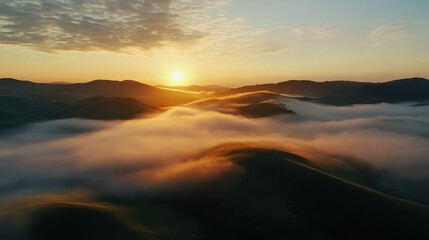 Fototapeta premium A breathtaking sunrise view over rolling hills with clouds floating above the landscape, creating a serene and tranquil atmosphere.