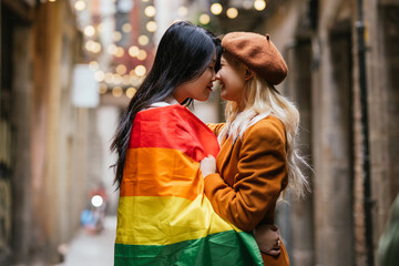 Lesbian couple sharing a tender moment under rainbow flag