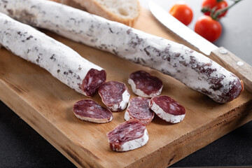 Fuet.Dry cured fuet sausage on black slate background