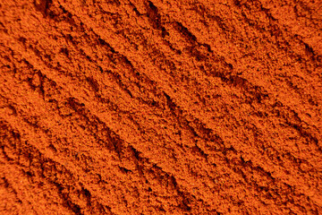 Abstract terracotta striped background of scattered paprika seasoning