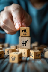 Shopping Cart Icon,  A person is placing a wooden block with a person icon on top of a shopping cart icon, surrounded by various other icons on a wooden table