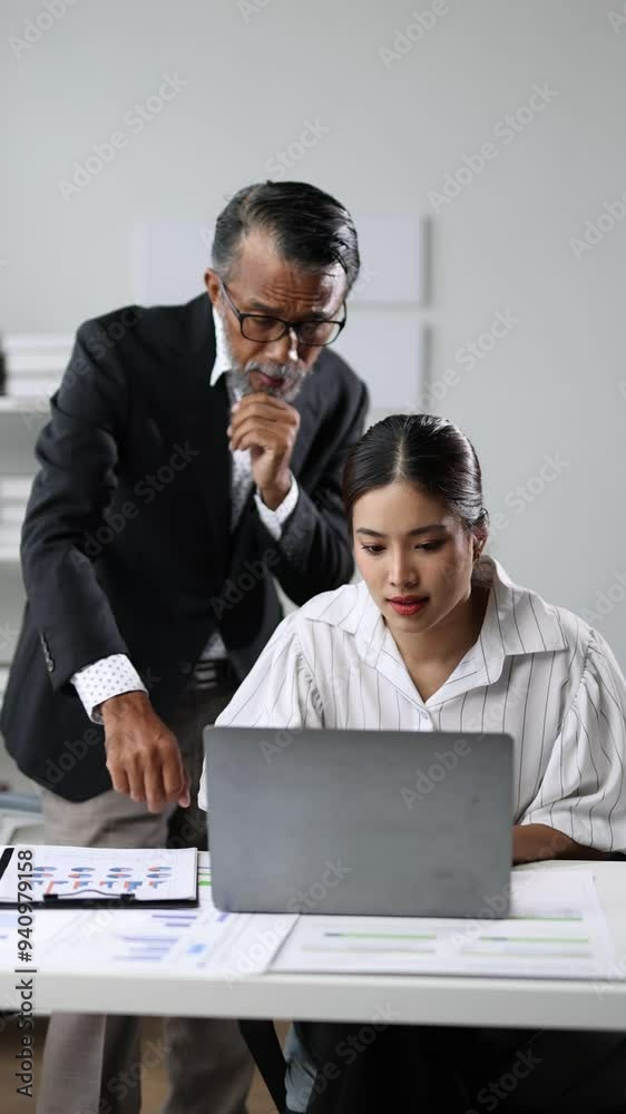 Wall mural Experienced manager mentoring young staff. Senior manager guiding young employee on laptop in modern office, collaborating on a project. Professional mentorship, teamwork, and workplace interaction.