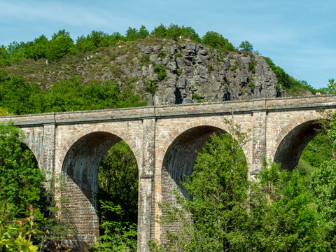 Clecy, Normandy, France, May 10, 2024. Railway viaduct made of stone against the background of a mountain in the town of Cleacy in Normandy, rocks green nature