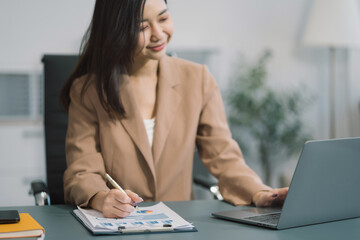 Fototapeta premium Business documents on the desk with a laptop and a Tablet with graphs, business diagrams and women working in the office.