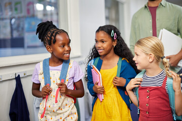 Three schoolgirls in school hallway talking to each others