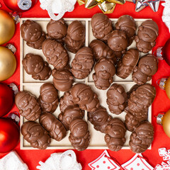 Chocolates in the shape of Christmas figures on the red background top view