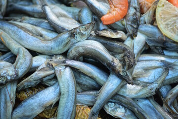 a pile of small grey sea fish and red boiled shrimps on the street