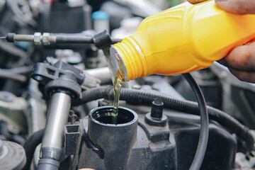 Fototapeta premium A man is pouring oil into a car engine
