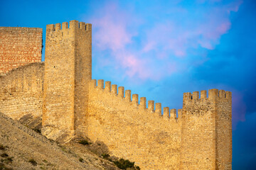 Naklejka premium Detail of the high crenellated towers and walls of the Albarracin castle fortress, Teruel, Aragon, Spain, with golden evening light