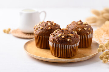 Chocolate almond muffin on wooden plate with white background