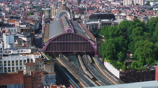 Brussels skyline emerges as clouds drift across the cityscape, showcasing iconic architecture and vibrant green spaces from an aerial perspective