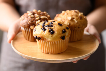 Vanilla chocolate chips muffin, Chocolate almond muffin and Vanilla almond muffin on wooden plate holding by hand