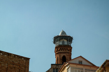Obraz premium Brick tower with ornament on the roof near an old building
