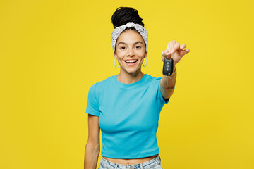 Young happy excited Latin woman wear blue top t-shirt headband casual clothes hold stretch hands to camera with hands car key fob keyless system isolated on plain yellow background. Lifestyle concept