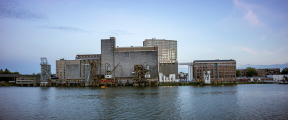 Wide panorama of old industrial processing factory and silo building on the shore of the Maas river in the Dutch harbour infrastructure port city of Rotterdam © Maarten Zeehandelaar