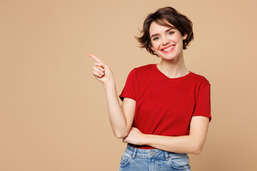 Young smiling happy woman she wear red t-shirt casual clothes point index finger aside on empty...