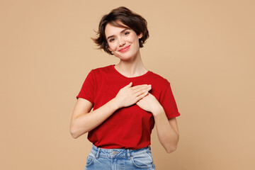 Young smiling happy thankful grateful woman wear red t-shirt casual clothes put folded hands on...