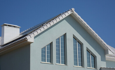 Beautiful windows of the facade of the house with soffit, white roof and solar panels