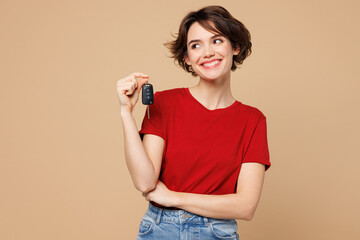 Young smiling happy woman wear red t-shirt casual clothes hold in hand car key fob keyless system...