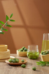 Front view of fresh green olives containing on wooden bowls decorated with leaves on brown background. Scene for advertising. Olive oil contains large amounts of antioxidants