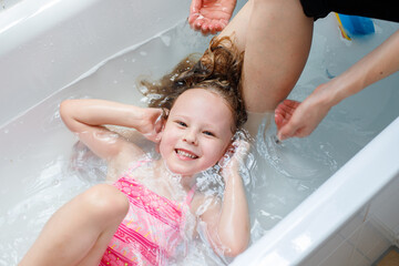 A small child takes a bubble bath . Mother washing the baby. Baby hygiene. Shampoo, hair care...