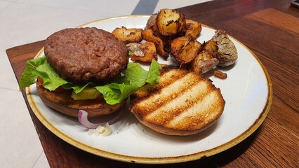 Open Burger on a Plate with Side of Crispy Potatoes – A Delicious Meal